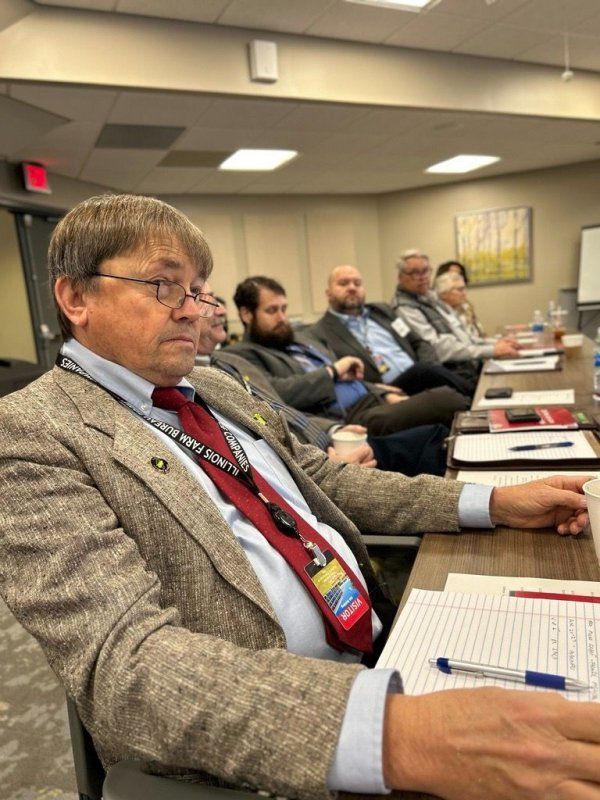 A man in a suit and tie is sitting at a table with other people.