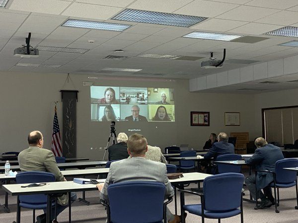 A group of people are sitting in front of a projector screen