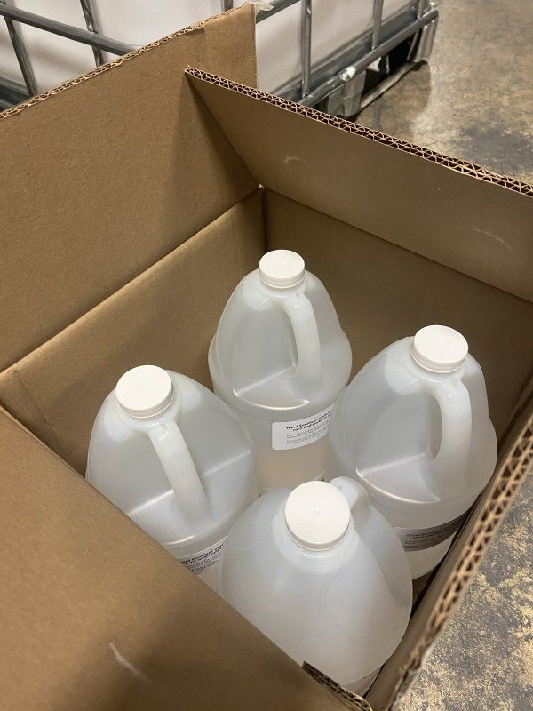 Four gallons of liquid are in a cardboard box.