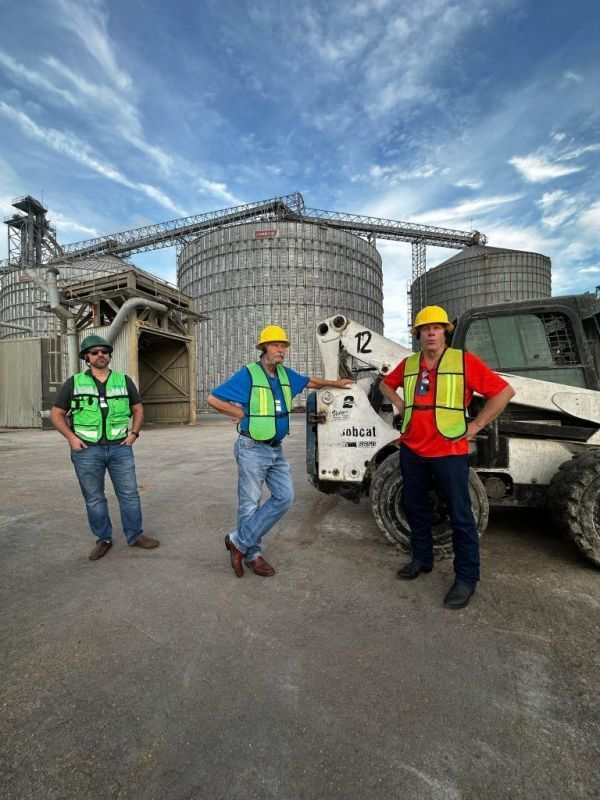 A group of construction workers are standing in front of a bulldozer.