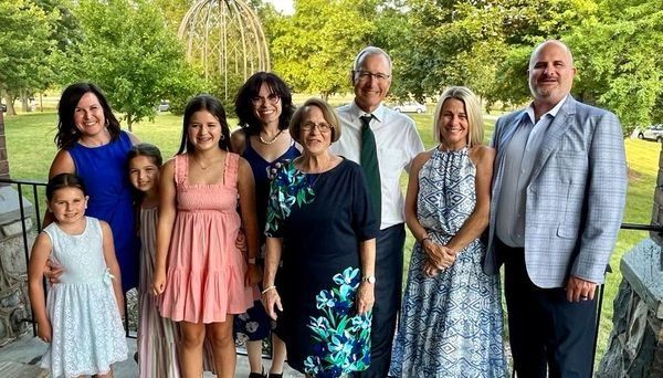 A large family is posing for a picture together in a park.