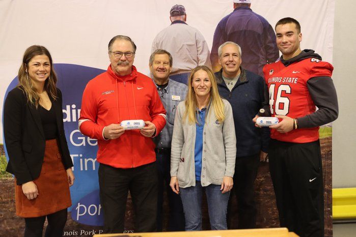 A group of people are posing for a picture and one of them is wearing a jersey with the number 16 on it.