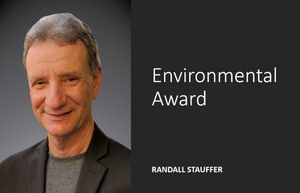 A man is smiling in front of a sign that says environmental award