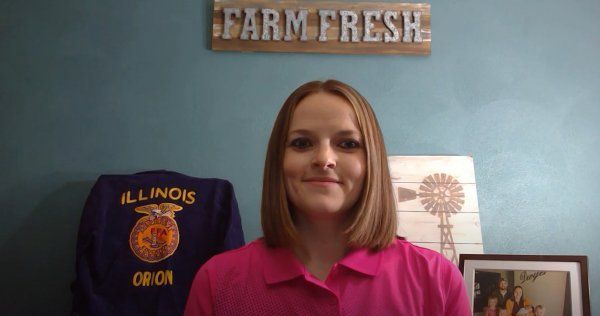 A woman in a pink shirt is standing in front of a sign that says farm fresh.