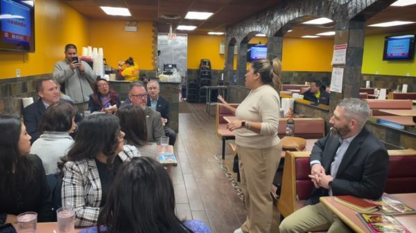 A woman is standing in front of a group of people in a restaurant.