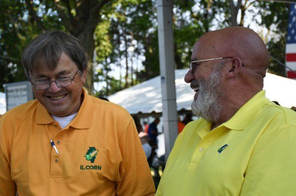 Two men wearing yellow shirts are standing next to each other and smiling.