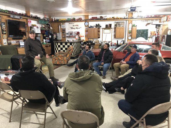 A group of men are sitting in a circle in a garage