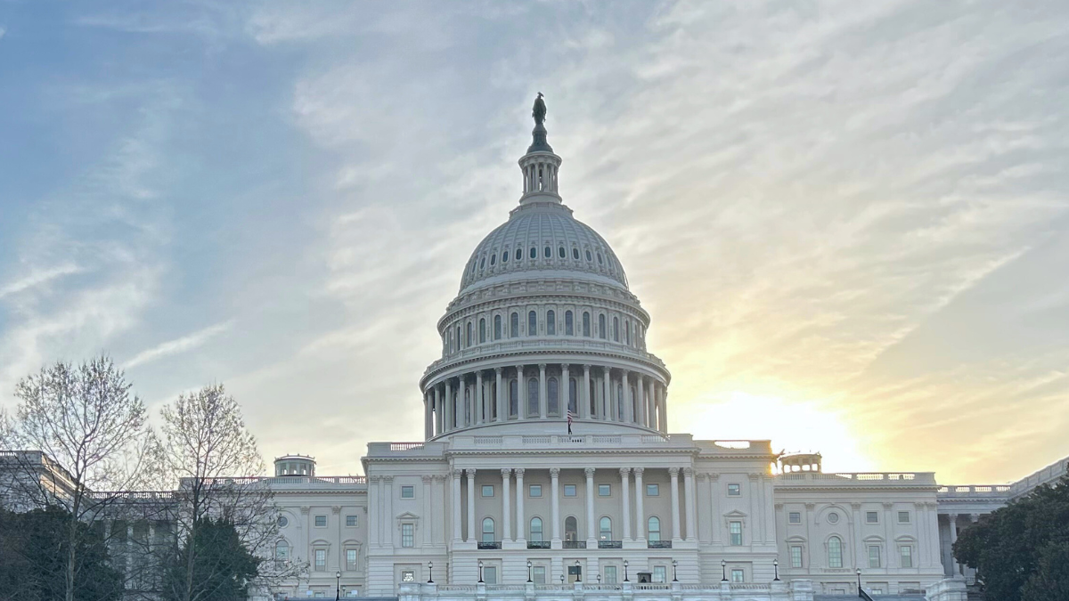 The sun is setting behind the capitol building in washington d.c.