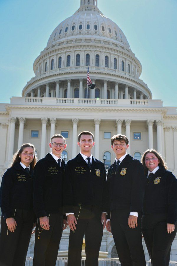 A group of people are standing in front of the capitol building.