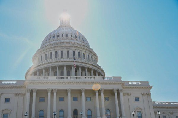 The sun is shining on the dome of the capitol building.