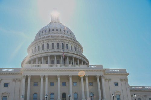 The sun is shining on the dome of the capitol building.