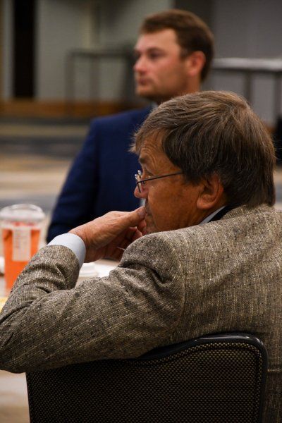 A man in a suit and glasses is sitting at a table.