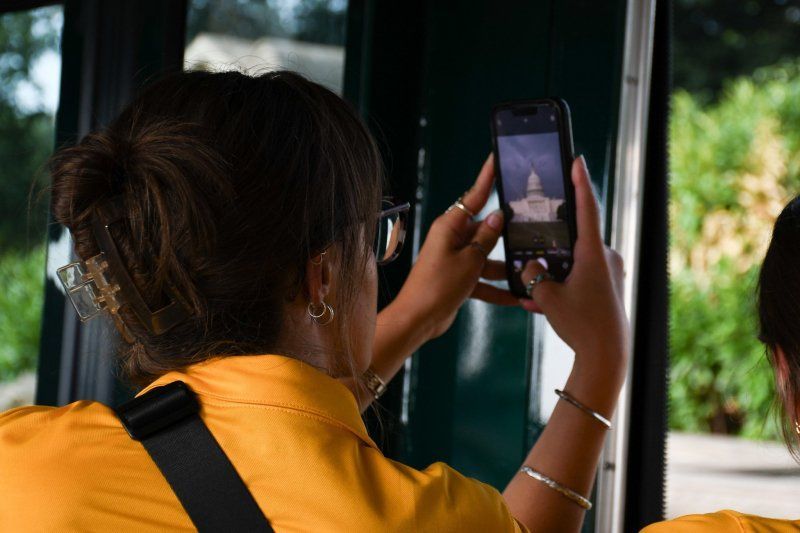 A woman is taking a picture of a building with her cell phone.