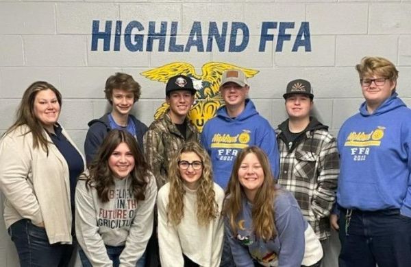 A group of people standing in front of a wall that says highland ffa