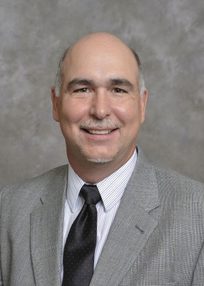 A man in a suit and tie is smiling for the camera.