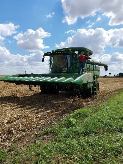 A man is driving a combine harvester in a field.