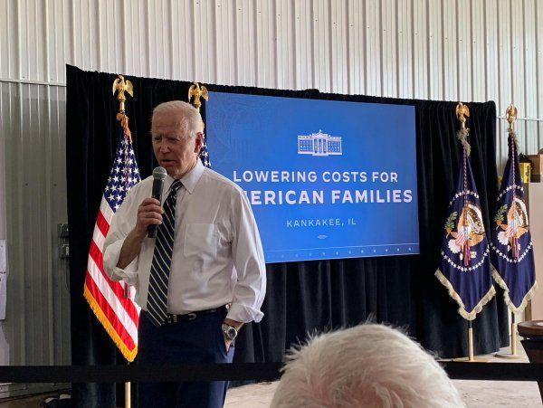 A man stands in front of a screen that says lowering costs for american families