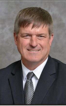 A man in a suit and tie is smiling for the camera