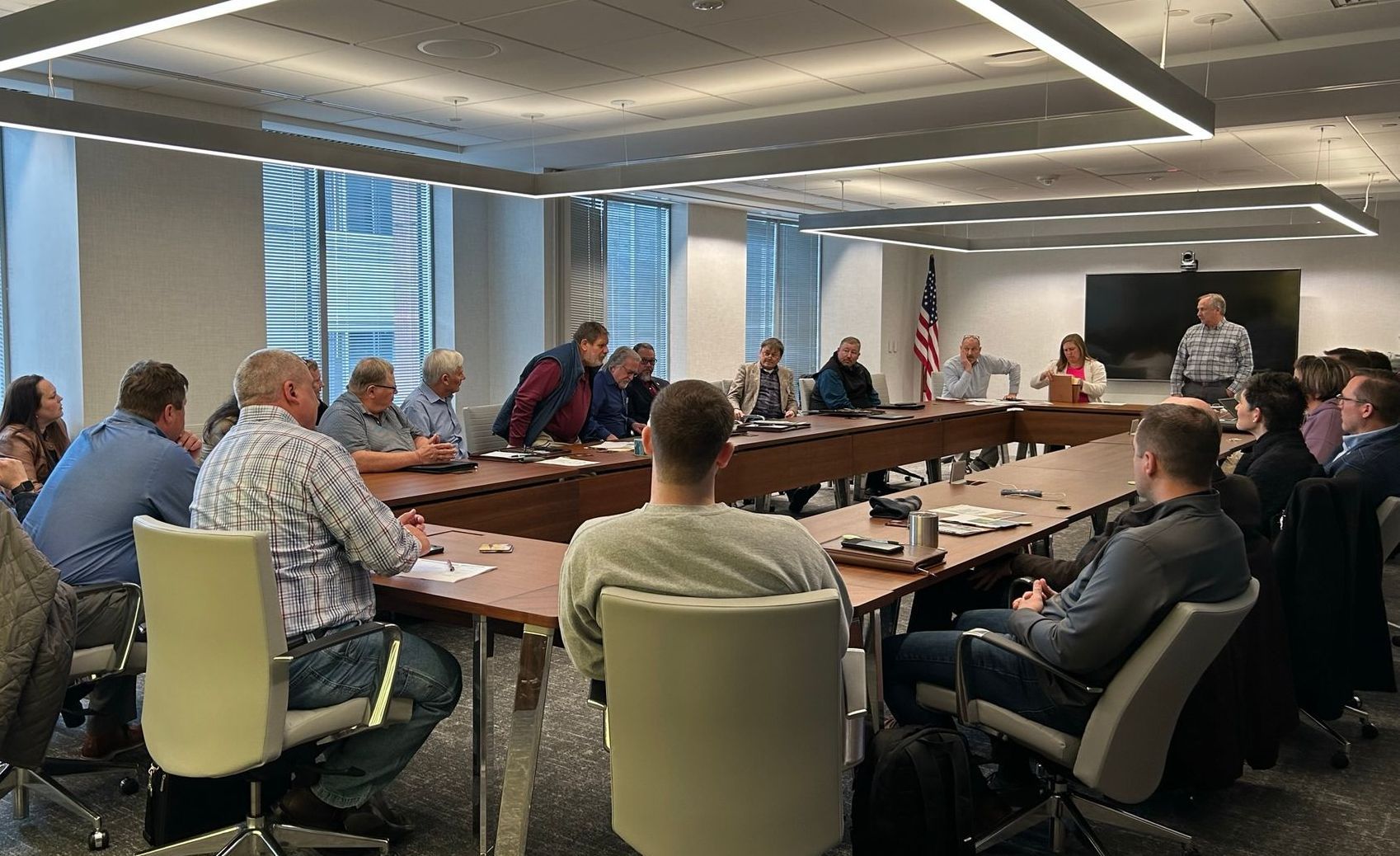 A group of people are sitting around a long table in a conference room.