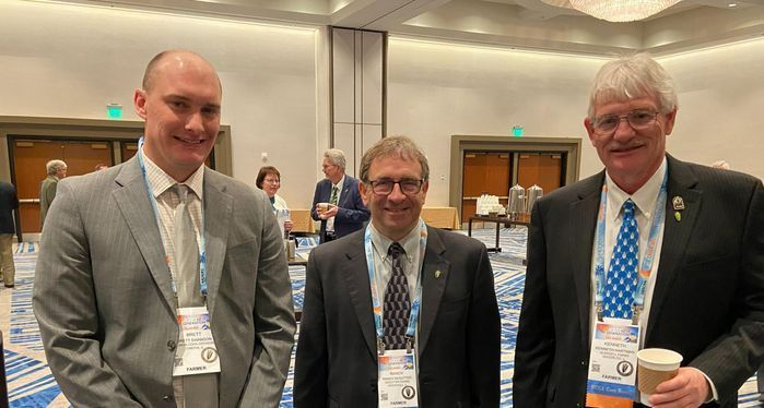 Three men in suits and ties are posing for a picture in a conference room.