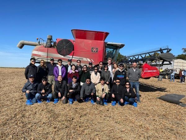 A group of people are posing for a picture in front of a combine harvester.