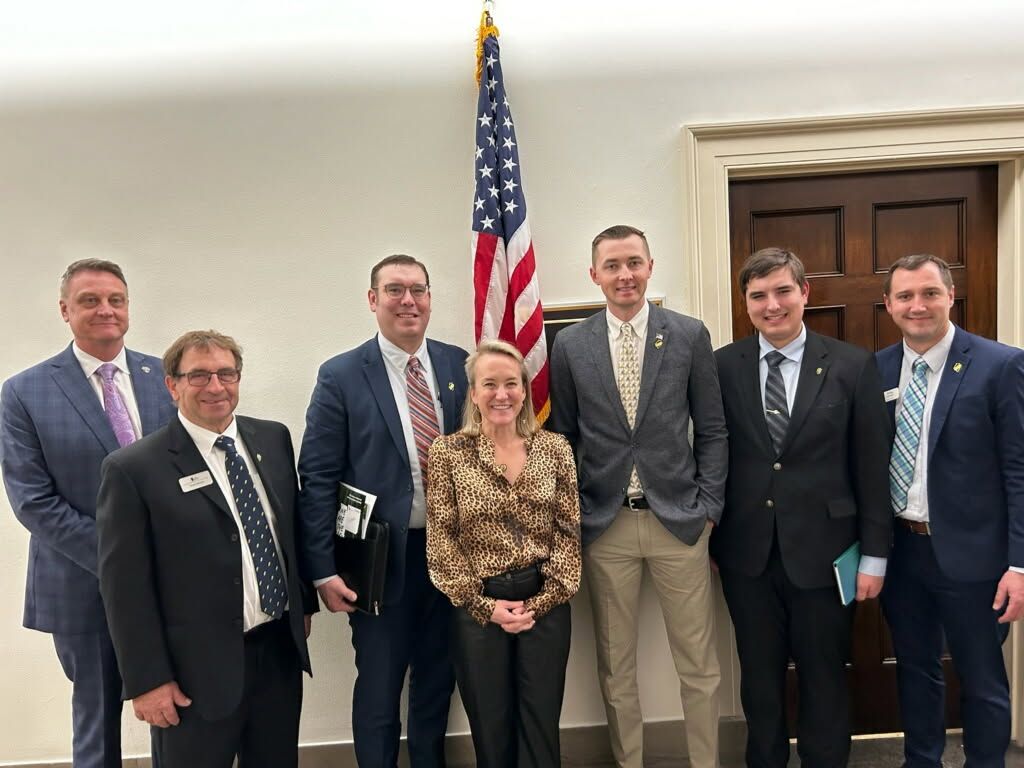 Group of people in suits posing near an American flag.