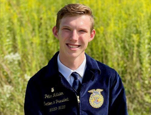 A young man in a blue jacket and tie is smiling for the camera.