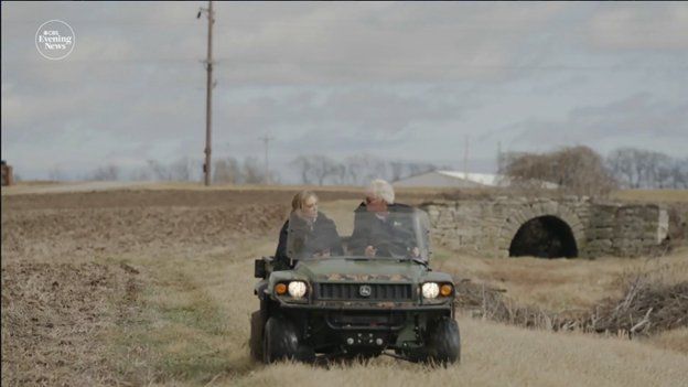 A man and a woman are driving a vehicle on a dirt road.