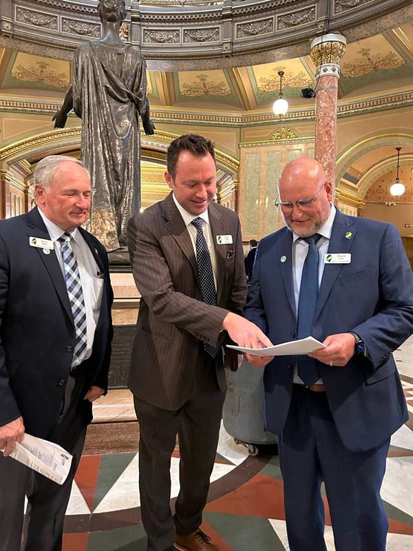 Three men in suits and ties are standing next to each other in front of a statue.