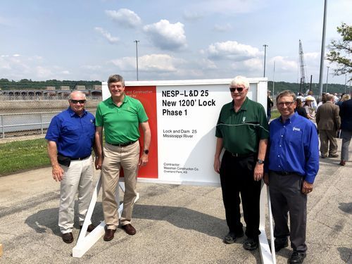 A group of men are standing in front of a sign that says phase 1.