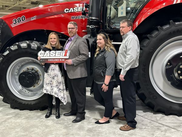 A group of people standing in front of a case tractor