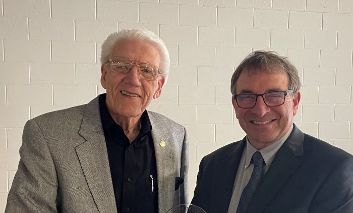 Two men in suits and ties are standing next to each other and smiling.