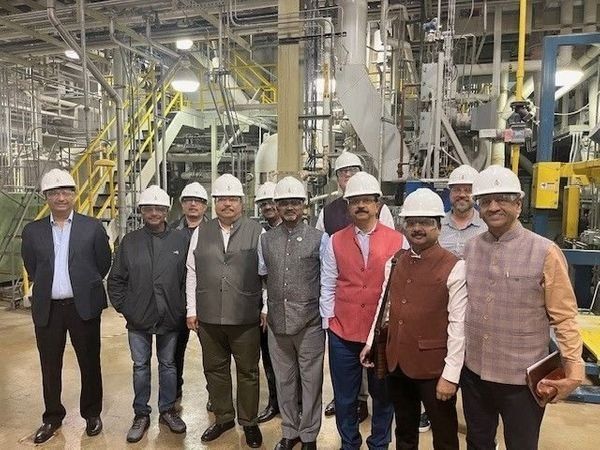 A group of men wearing hard hats are standing in a factory.