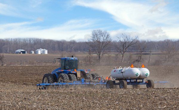 A tractor is plowing a field with a trailer attached to it.
