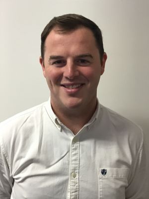 A man in a white shirt is smiling for the camera.