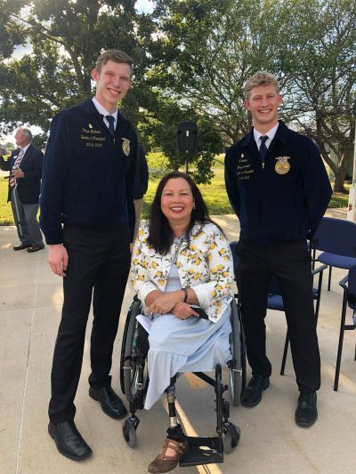 A woman in a wheelchair is posing for a picture with two men