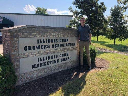 A man is standing in front of a sign for the illinois corn growers association.