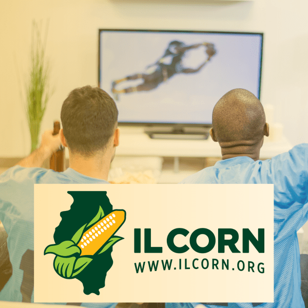 Two men sitting in front of a television with a sign that says il corn www.ilcorn.org