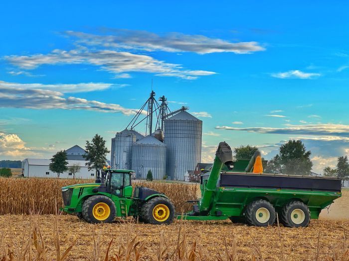 A green tractor is pulling a trailer in a field.