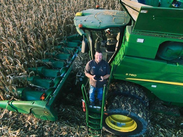 A man is standing next to a green john deere combine harvester