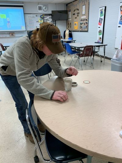 A man in a hat is reaching for a cup on a table