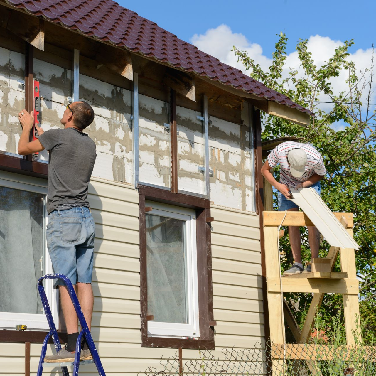 A handyman is installing exterior siding on a house for home improvement. A handyman is installing exterior siding on a house for home improvement.