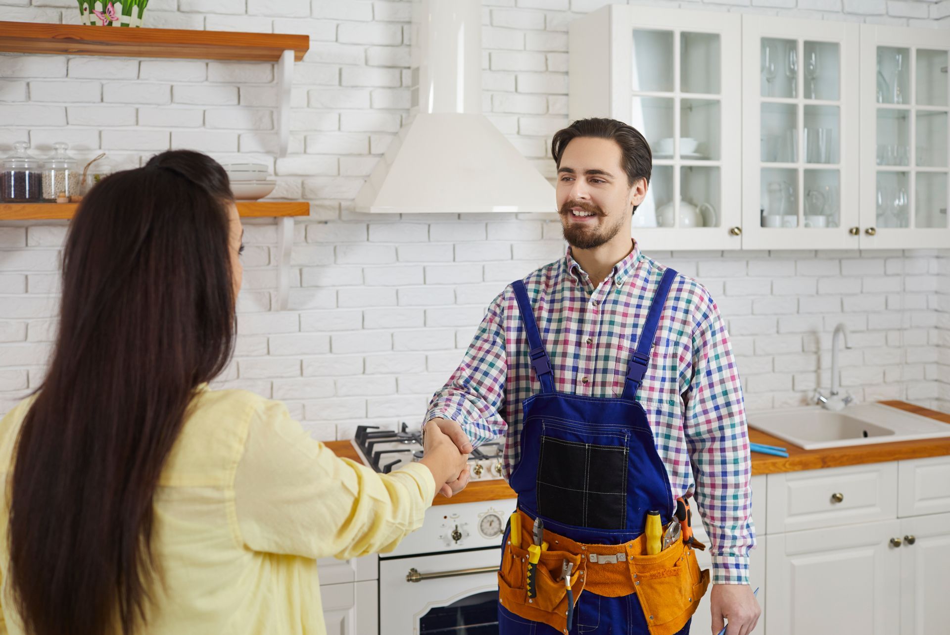 A handyman greeting a homeowner before starting repair services in the kitchen.