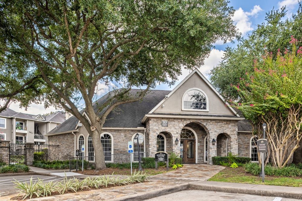 the clubhouse with a lot of windows and trees in front of it at Marquis on Westheimer in Houston, TX.