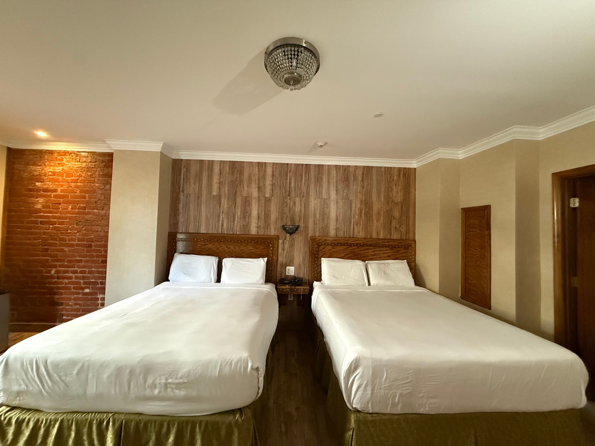 Two beds in a hotel room with brick and wood accent walls.