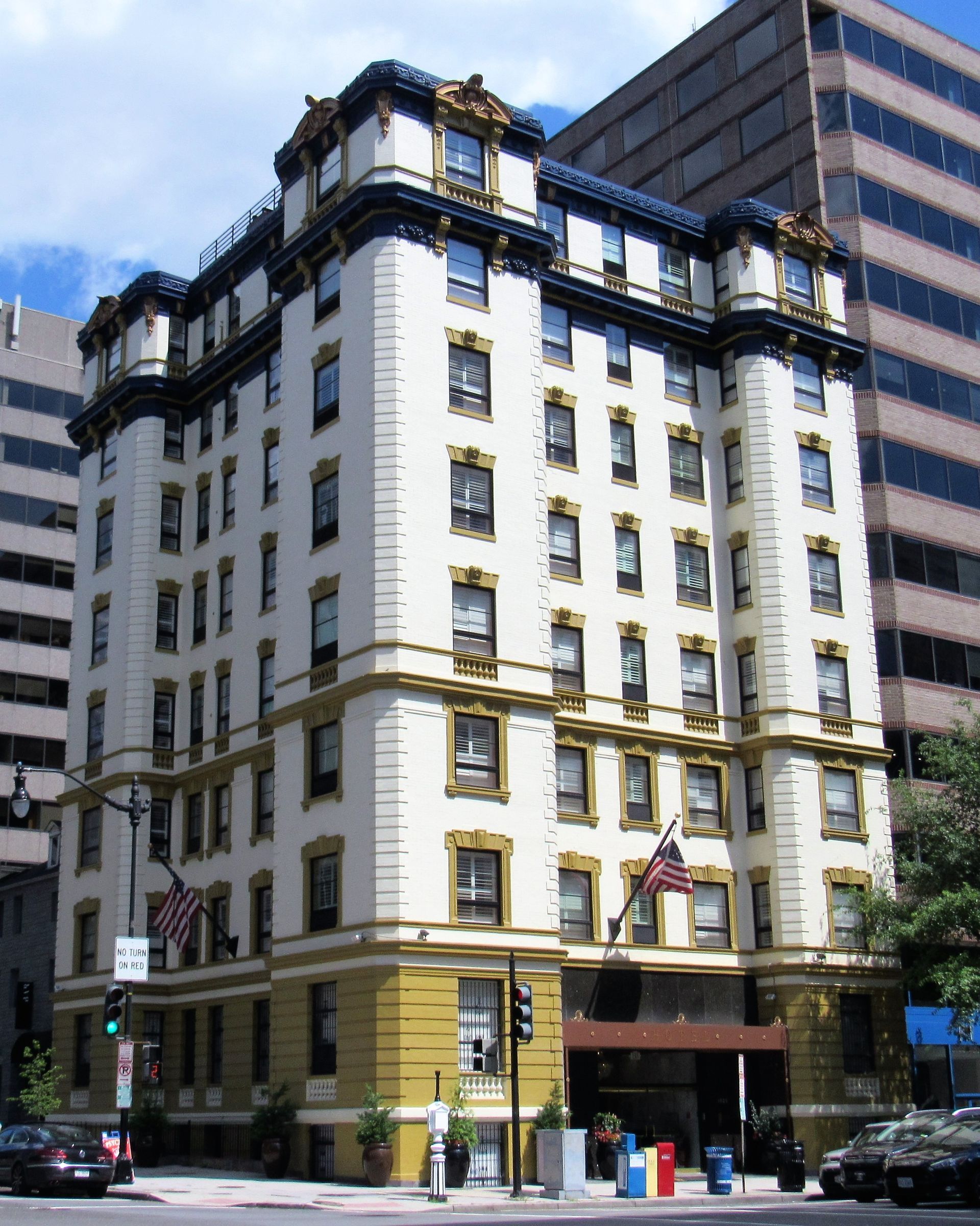 Ivory brick building with dark blue trim, ornate top. Cars parked out front.