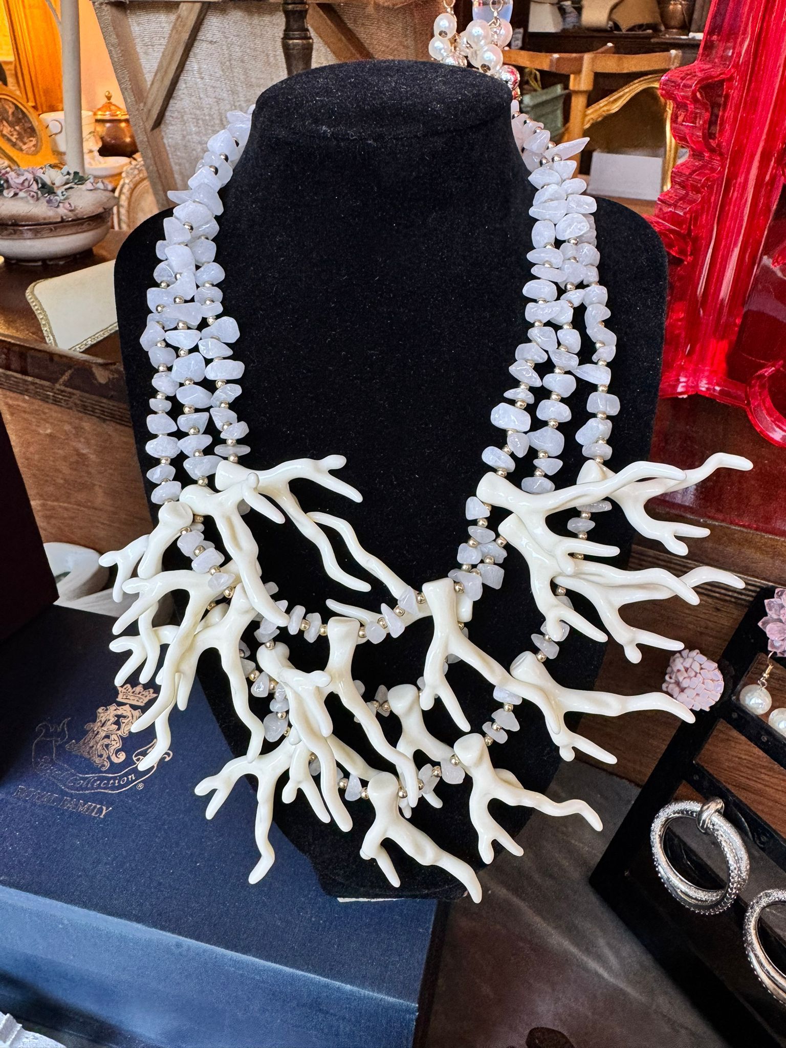 Un manichino nero indossa una collana con perle di corallo bianco.