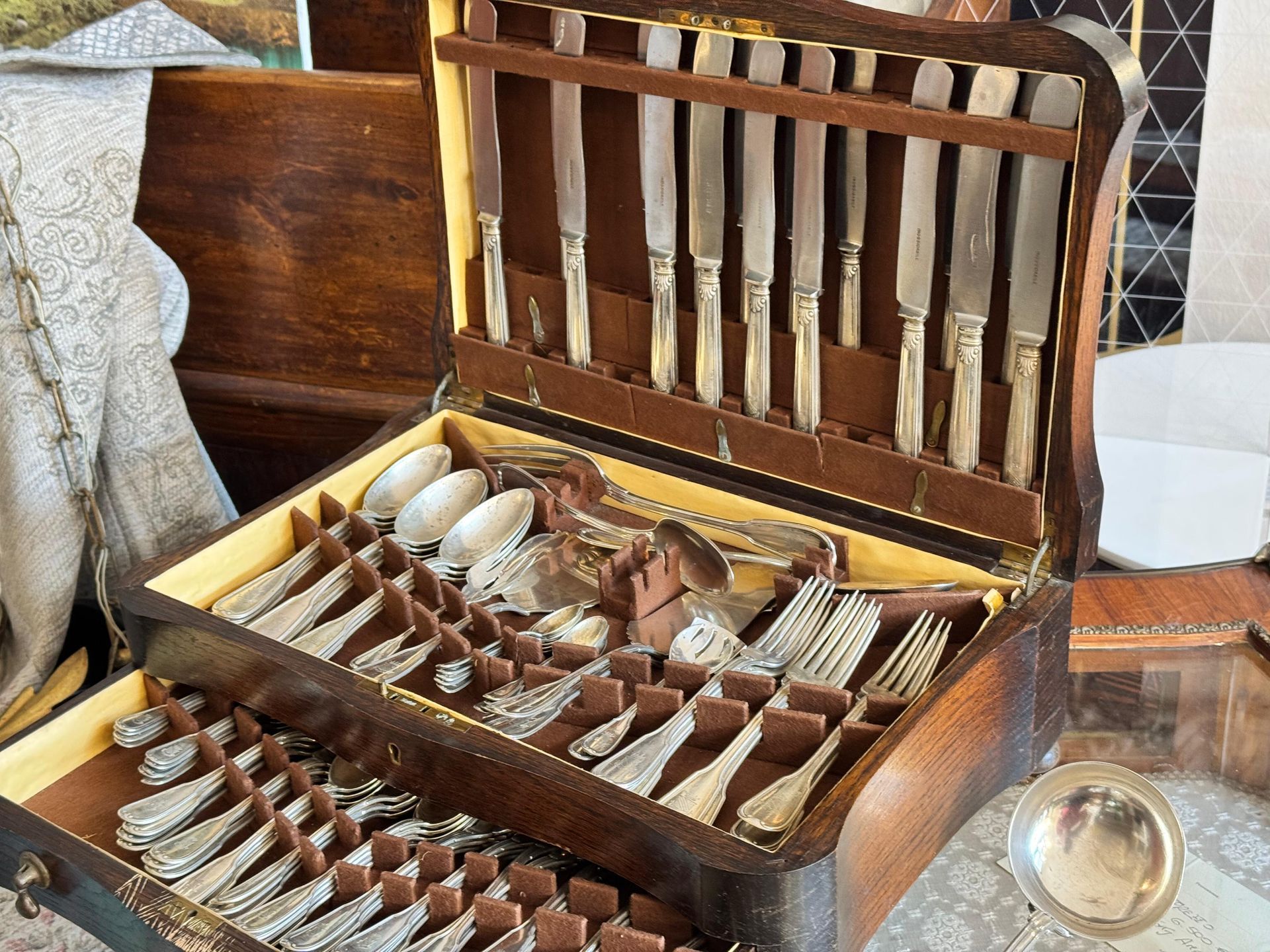Una scatola di legno piena di posate e coltelli su un tavolo.