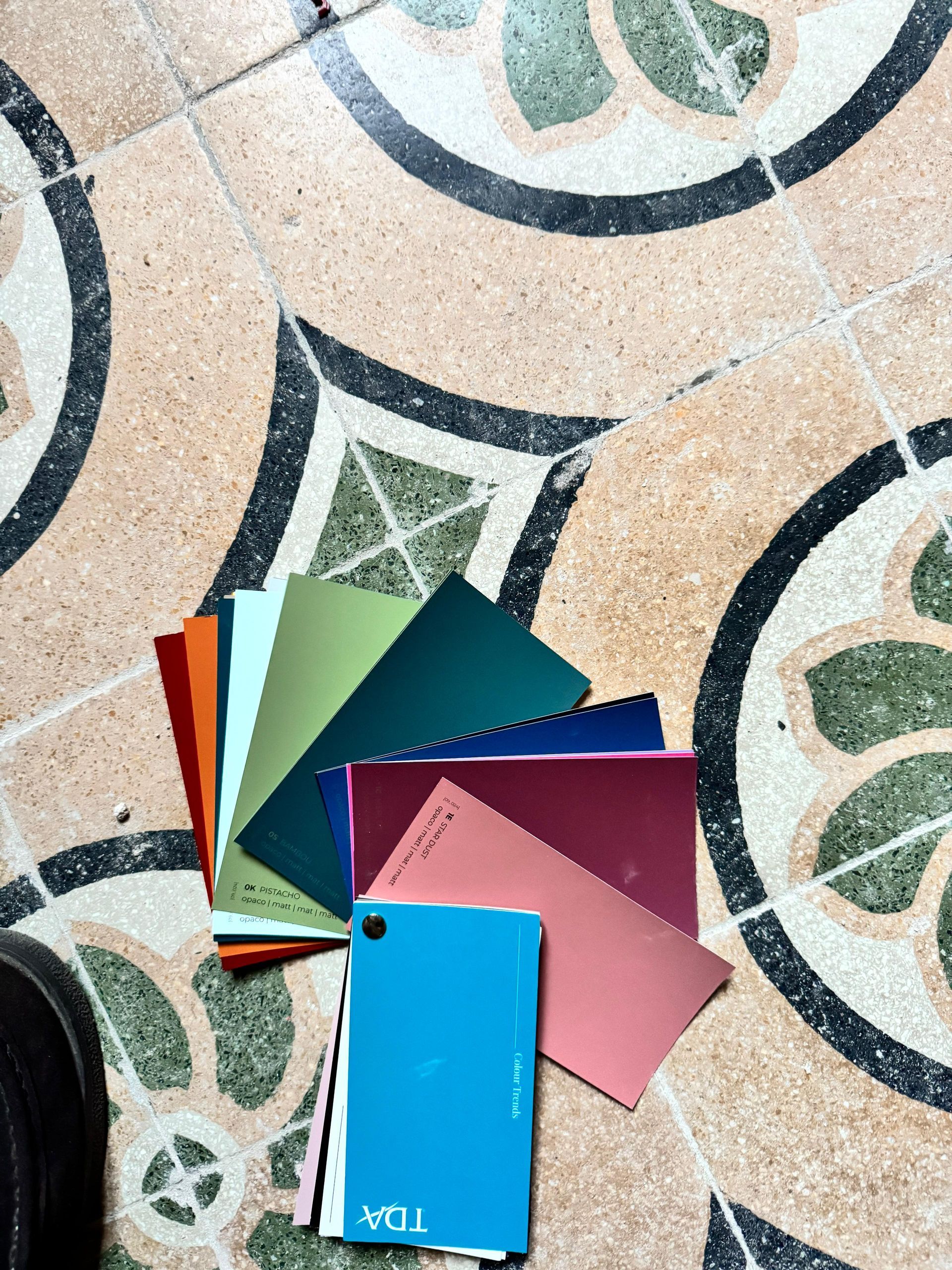 Un mucchio di fogli di carta di diversi colori su un pavimento piastrellato