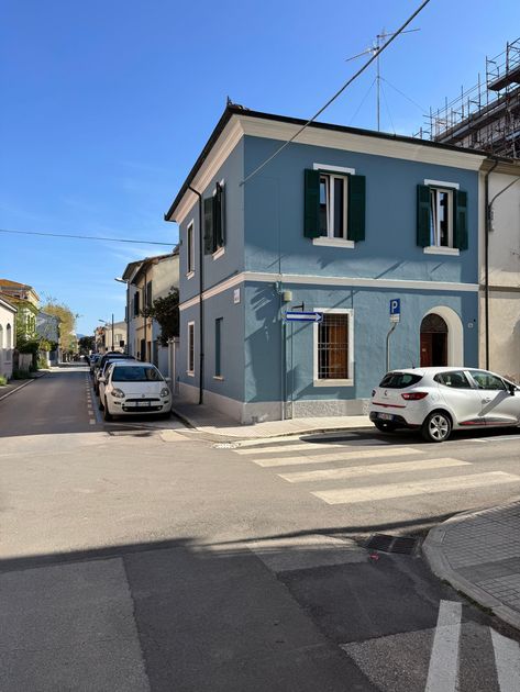 Un'auto bianca è parcheggiata davanti a un edificio blu